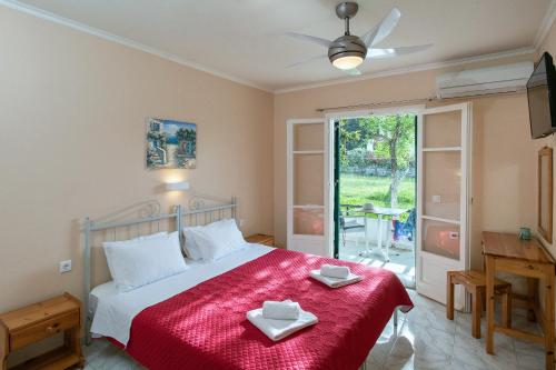 a bedroom with a large bed with a red blanket at Damaskis Studios in Kassiopi