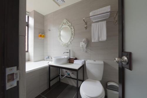 a bathroom with a toilet and a sink and a mirror at Herb Art Hotel in Keelung