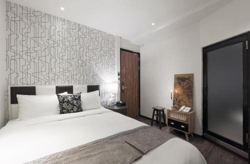 a bedroom with a large white bed and a wall at Herb Art Hotel in Keelung