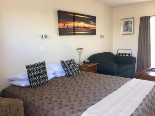 a bedroom with a bed with a couch and a television at ASURE Kapiti Court Motel in Paraparaumu Beach