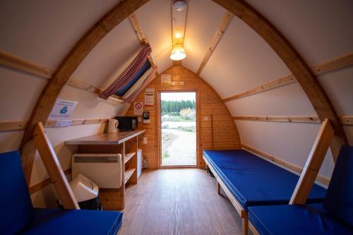 a room in a tiny house with a table and benches at Badaguish forest lodges and camping pods in Aviemore