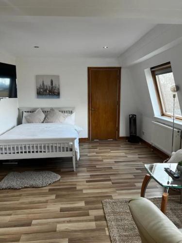a bedroom with a white bed and a wooden floor at Quirky studio flat selfcontained in London
