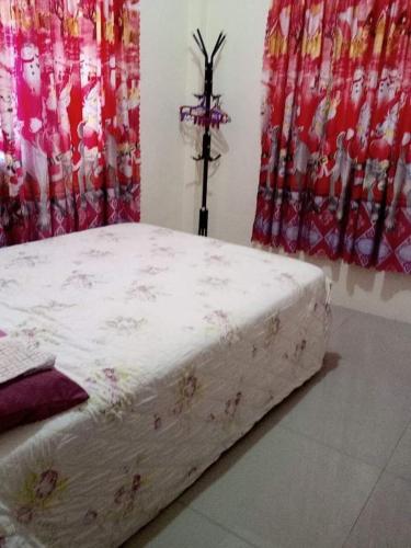 a bed sitting in a room with red curtains at Little bridges mini bar and rooms in Mambajao