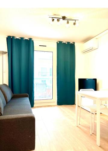 un soggiorno con tende blu, tavolo e divano di Residence Californie a Nizza
