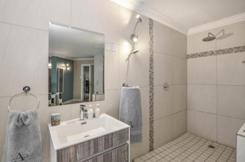 a white bathroom with a sink and a shower at Atlantic Breeze in Cape Town