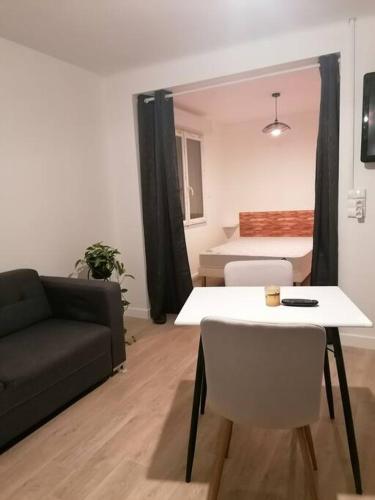 een woonkamer met een bank, een tafel en een bed bij Grand studio indépendant in Saint-Paul-lès-Dax