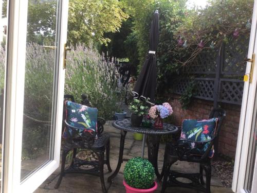 a patio with a table and chairs and an umbrella at Oakleigh 1 bed ground floor garden view apartment FREE ONSITE PARKING in Stratford-upon-Avon