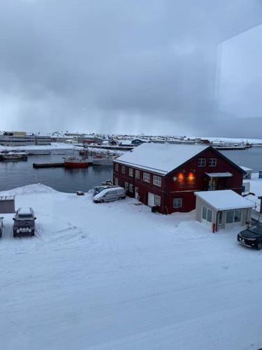 a house in the snow with cars parked next to it at Rooftop view apartment in Vardø