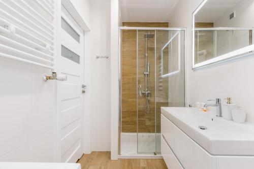 a white bathroom with a shower and a sink at Apartment Rybacka with Parking&Balcony by Renters in Międzywodzie