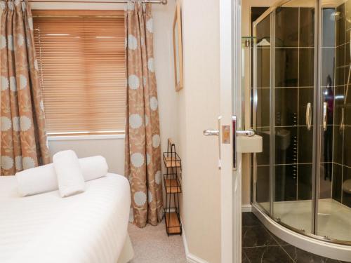 a bedroom with a shower and a bed and a window at Highfield Lodge in Windermere