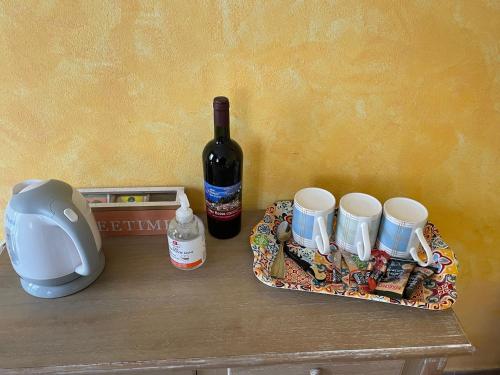 a table with a bottle of wine and a tray with cups at Hotel Diffuso Il Portichetto sulla collina a Vezio Perledo in Perledo