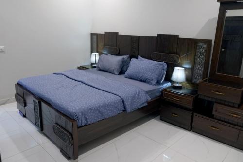 a bedroom with a bed with blue sheets and a tv at Al Rasheed Apartments second floor apartment in Karachi
