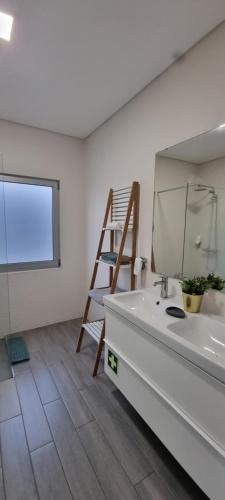 a bathroom with a sink and a mirror and a ladder at Bay House - Seascape Apartment in Ponta Delgada