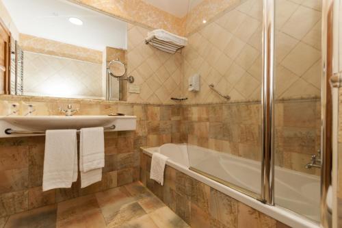 a bathroom with a tub and a sink and a shower at Hotel Comendador in Carranque
