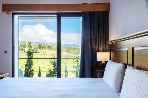 sypialnia z łóżkiem i dużym oknem w obiekcie Azores Green Woods Villa w mieście São Vicente Ferreira