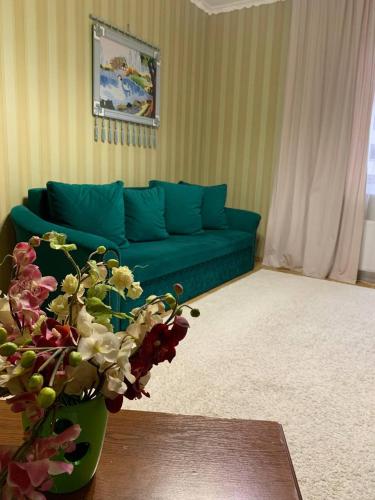 a living room with a green couch and a vase with flowers at ГОК Віват in Morshin