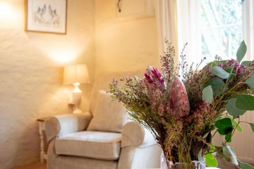 a vase of flowers on a table in a living room at The Pack Horse Exmoor National Park Allerford Riverside Cottage & Apartments in Minehead