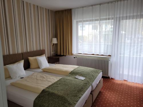 a hotel room with two beds and a window at Kurparkhotel-Gemünd in Gemünd