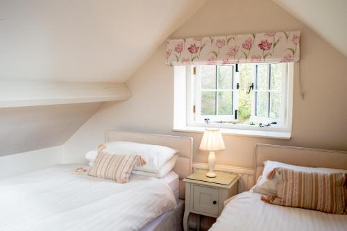 two beds in a attic bedroom with a window at The Pack Horse Exmoor National Park Allerford Riverside Cottage & Apartments in Minehead