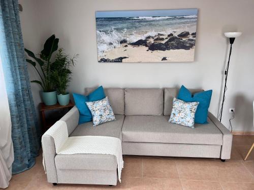 sala de estar con sofá gris y almohadas azules en Casa Esmeralda, en Corralejo