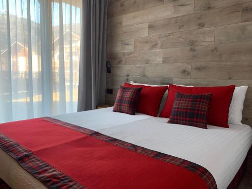 un grande letto con cuscini rossi e un muro di mattoni di Al Bait Ross a Bormio