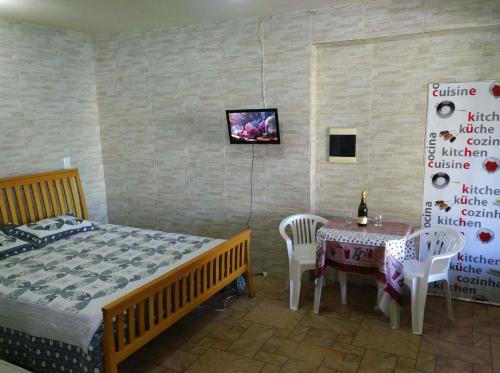 a bedroom with a bed and a table and a tv at Itaipuaçu Residencia Cajueiros I in Itaipuaçu