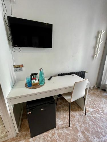 a white desk with a television on a wall at Madison Rooms in Sitges