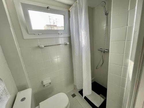 a white bathroom with a toilet and a window at Madison Rooms in Sitges
