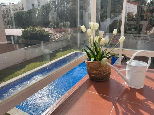 een vaas met bloemen op een tafel naast een zwembad bij Apartamento Paris I in Miami Platja