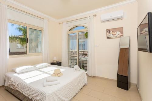 a white bedroom with a bed and a balcony at Villa Andree in Paralimni