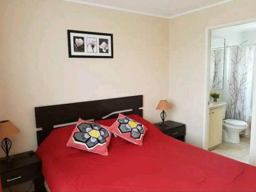 Un dormitorio con una cama roja con dos almohadas. en Casa condominio Pucón, piscina, en Pucón