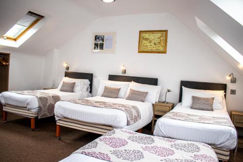 3 camas en una habitación con paredes blancas en The Rostrevor Inn en Rostrevor