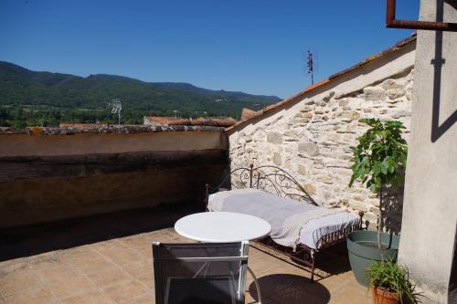 einen Balkon mit einem Tisch und einer Bank an einer Wand in der Unterkunft La Tour de l'Ange in Hérépian