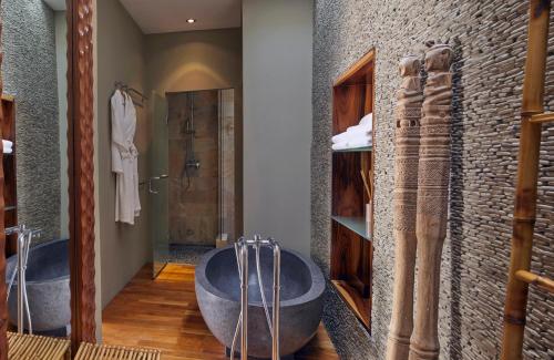 a bathroom with two tubs and a stone wall at The Giri Residence in San Juan Bautista