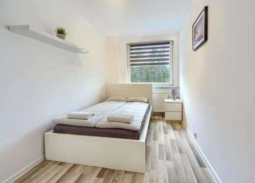 een witte slaapkamer met een bed en een raam bij Mieszkanie Zacisze - NoclegiSopot in Sopot