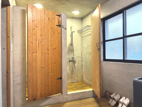 a bathroom with a shower with a wooden door at Swallows Hostel in Xiaoliuqiu