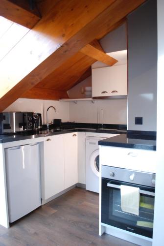 a kitchen with white appliances and a wooden ceiling at Altar Suites Caño Badillo by gaiarooms in León