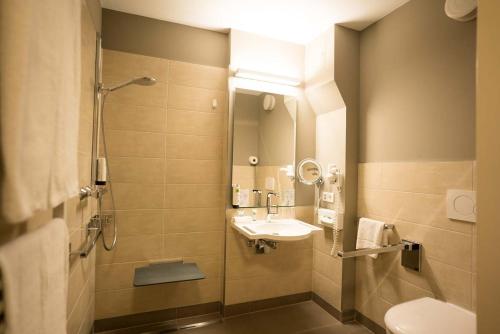 a bathroom with a sink and a shower and a toilet at Hotel Fulda Mitte in Fulda