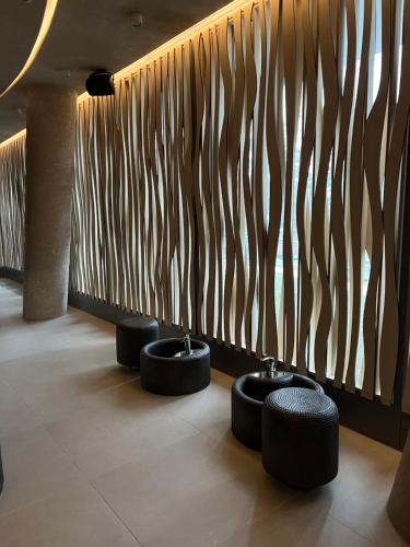 a lobby with three stools in front of a wooden wall at Apartament Morski Widok Międzyzdroje in Międzyzdroje