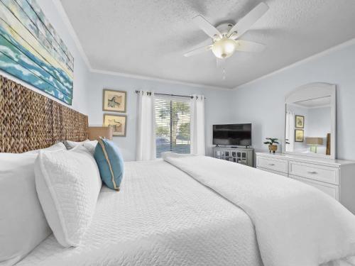 a bedroom with a white bed with a ceiling fan at Emerald Shores #1001 Condo in Panama City Beach