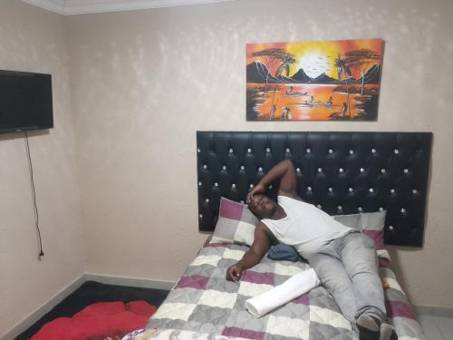 a man laying on a bed in a bedroom at TAU GUEST HOUSE in Elandsfontein