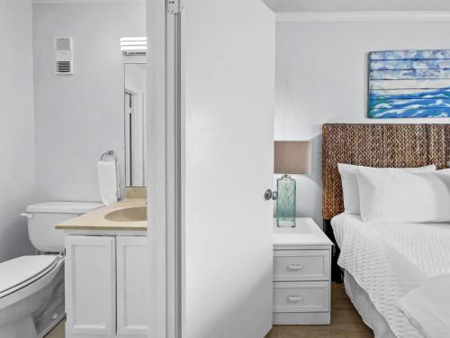 a white bathroom with a sink and a bed at Emerald Shores #1001 Condo in Panama City Beach
