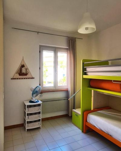 a bedroom with two bunk beds and a window at Il Poggiolo di Levante - Piscina e Ombrellone spiaggia prima fila incluso in Marcelli