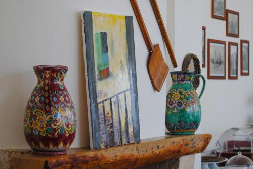 two vases sitting on a wooden shelf next to a painting at Hotel Giardino Giamperduto in Bernalda