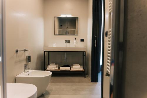 a bathroom with a sink and a toilet and a mirror at Arryvo Hotel in Lecce