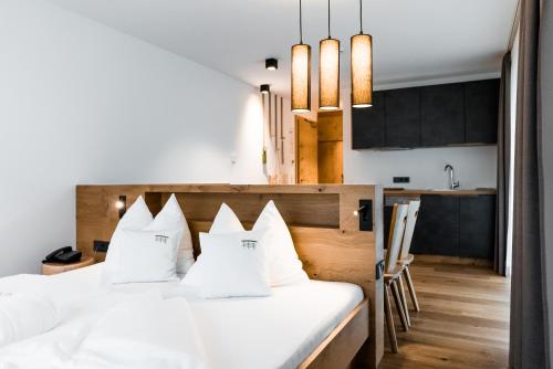 a bedroom with two white beds and a kitchen at JOAS natur.hotel.b&b in San Candido