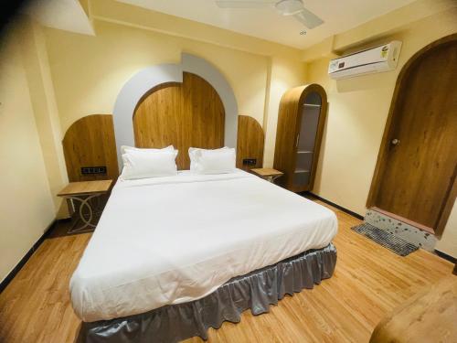 a large white bed in a room with wooden floors at Hotel Nova Bopal in Bodakdev