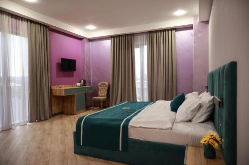 - une chambre avec un grand lit aux murs violets dans l'établissement DADIANI Inn, à Zugdidi