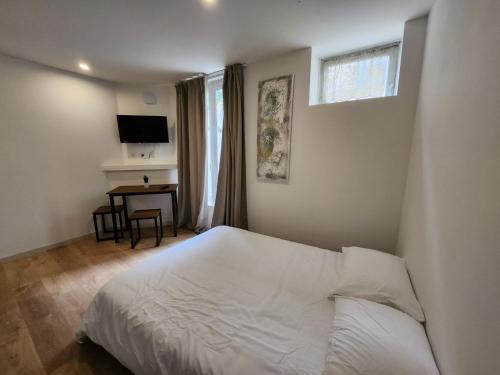 1 dormitorio con cama blanca y escritorio en Studio calme rdc coté cours en Bar-le-Duc