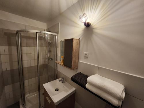 y un baño con lavabo de ducha y una luz en la pared. en Studio calme rdc coté cours en Bar-le-Duc